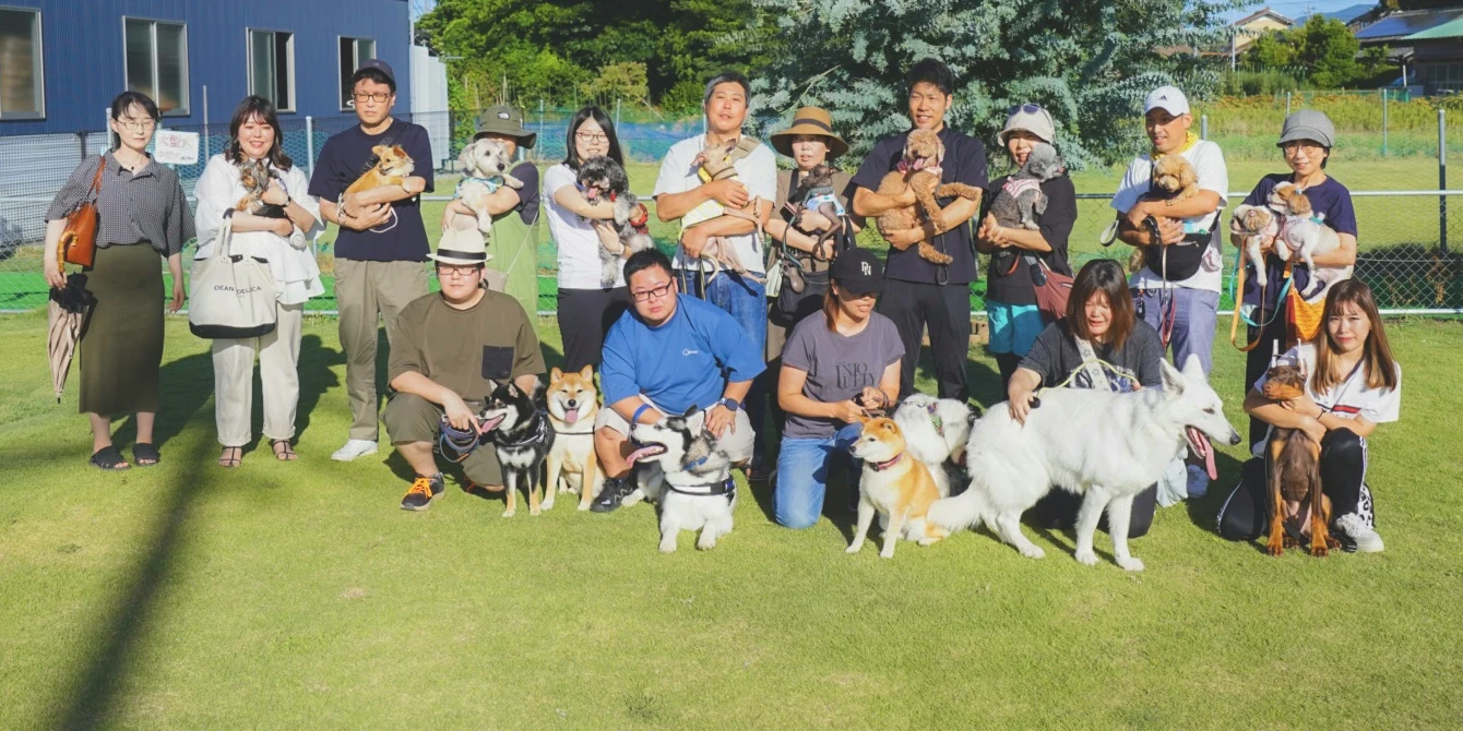 運営するドッグランの芝生で、飼い主さんと愛犬たちの集合写真